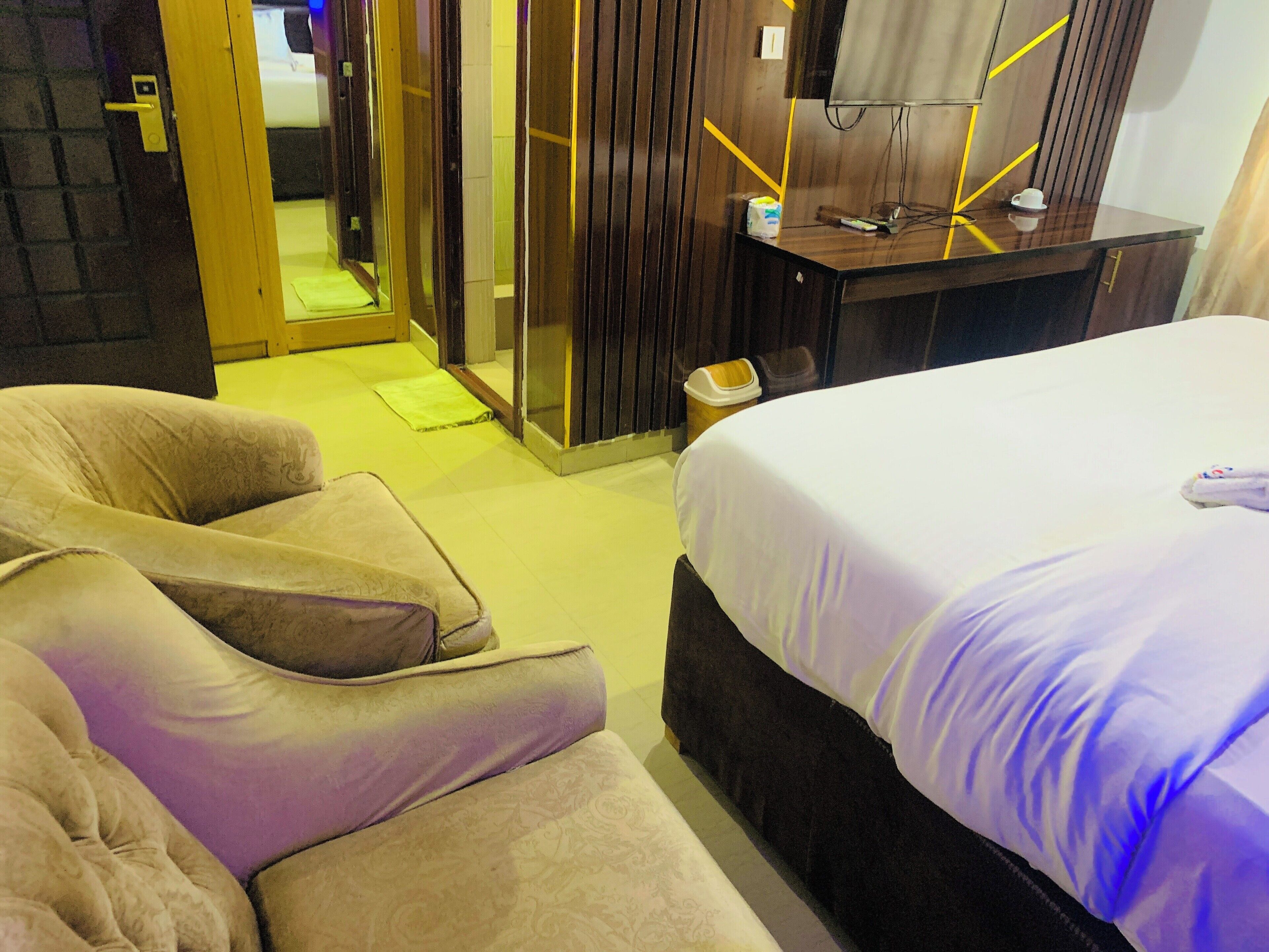 A hotel room with a bed, a sofa, a desk, and a mirror.