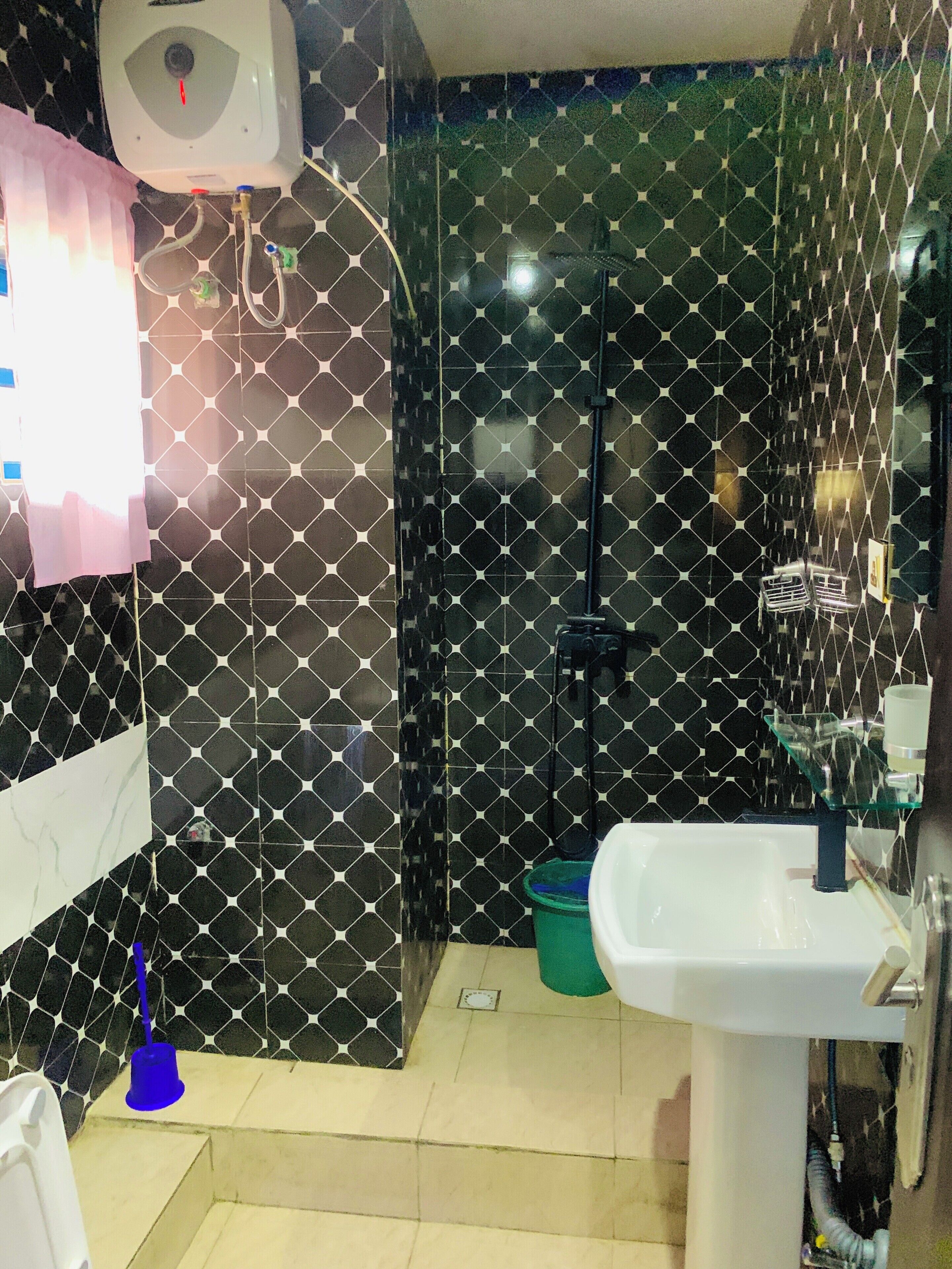 A bathroom with a black and white patterned wall, a white sink, and a handheld showerhead.