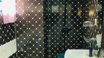 A bathroom with a black and white patterned wall, a white sink, and a handheld showerhead.