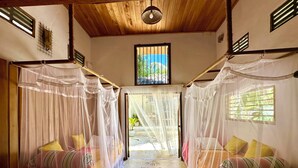 A room with two beds covered by mosquito nets, a wooden ceiling, and a view through an open door. - Deep Blue Sea Rental Villa (Matara)