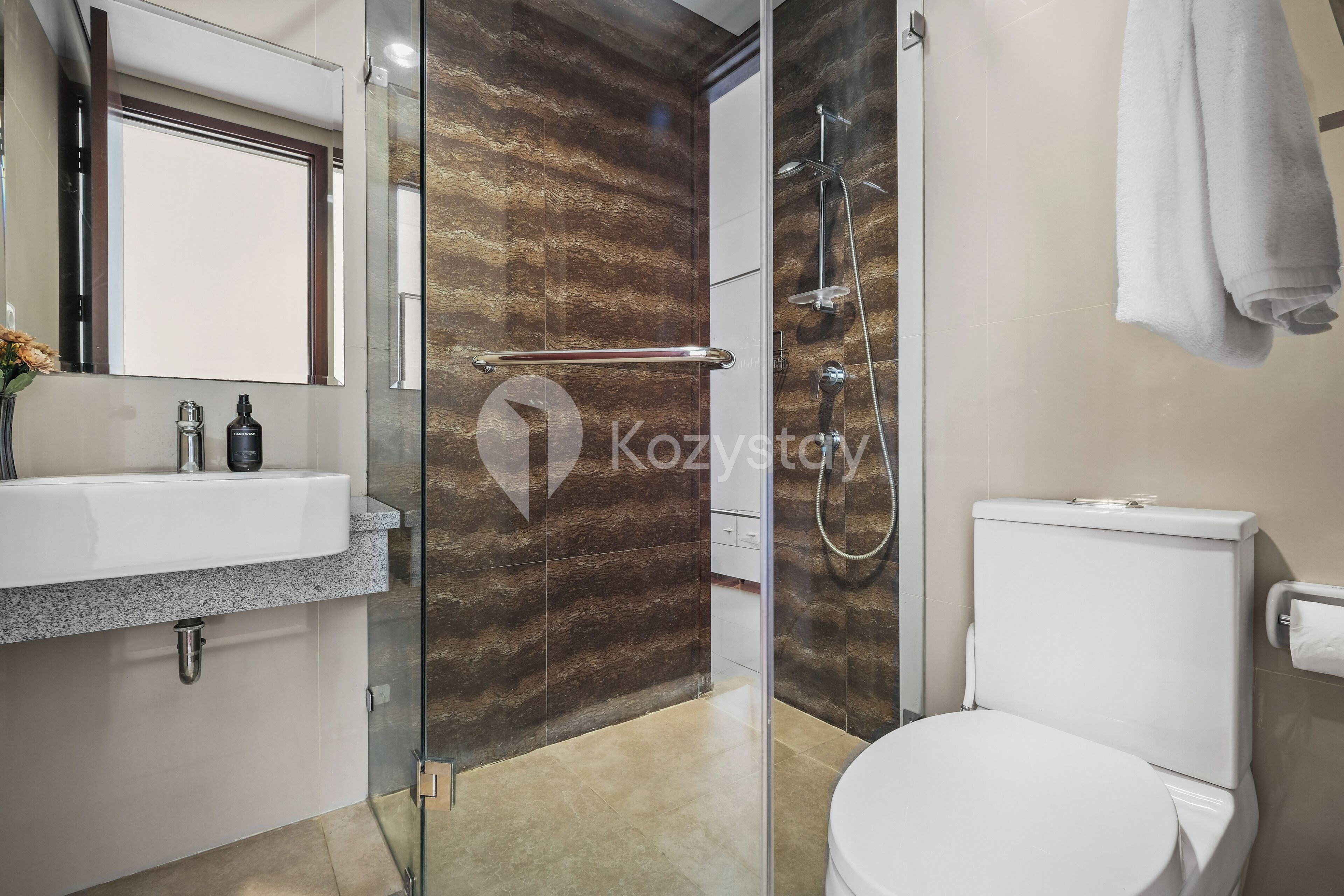 Un baño moderno con cabina de ducha de vidrio, inodoro blanco y lavamanos con encimera de granito.