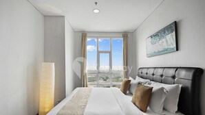 A modern hotel room with a large bed, a view of the cityscape, and a painting on the wall. - Averona by Kozystay - Taman Sari (Jakarta)