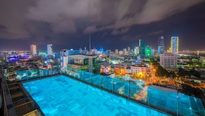 Una piscina en la azotea con vistas a la ciudad de noche.