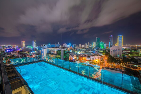 Una piscina en la azotea con vistas a la ciudad de noche.