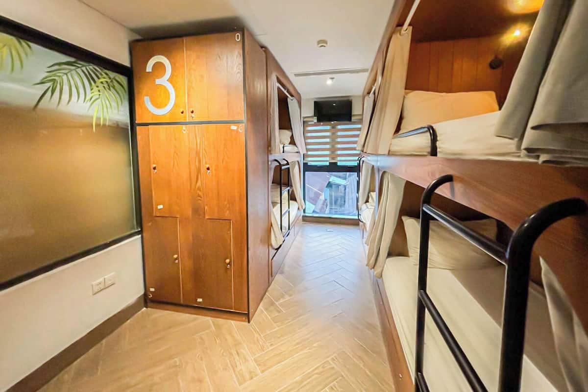 A compact, well-lit interior with a bunk bed, a wooden wardrobe with a number '3' sign, and a herringbone-patterned floor.