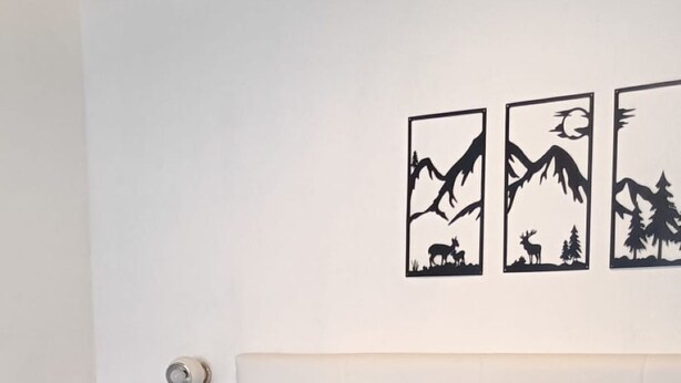 A bedroom with a bed, pillows, a nightstand, and wall art. - Tabià Iori:Cozy apartment in the historic center of Bormio, pets allowed (Bormio)
