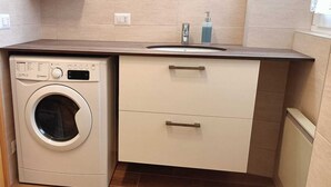 A compact laundry area with a washing machine, a sink, and a small cabinet. - Tabià Iori:Cozy apartment in the historic center of Bormio, pets allowed (Bormio)