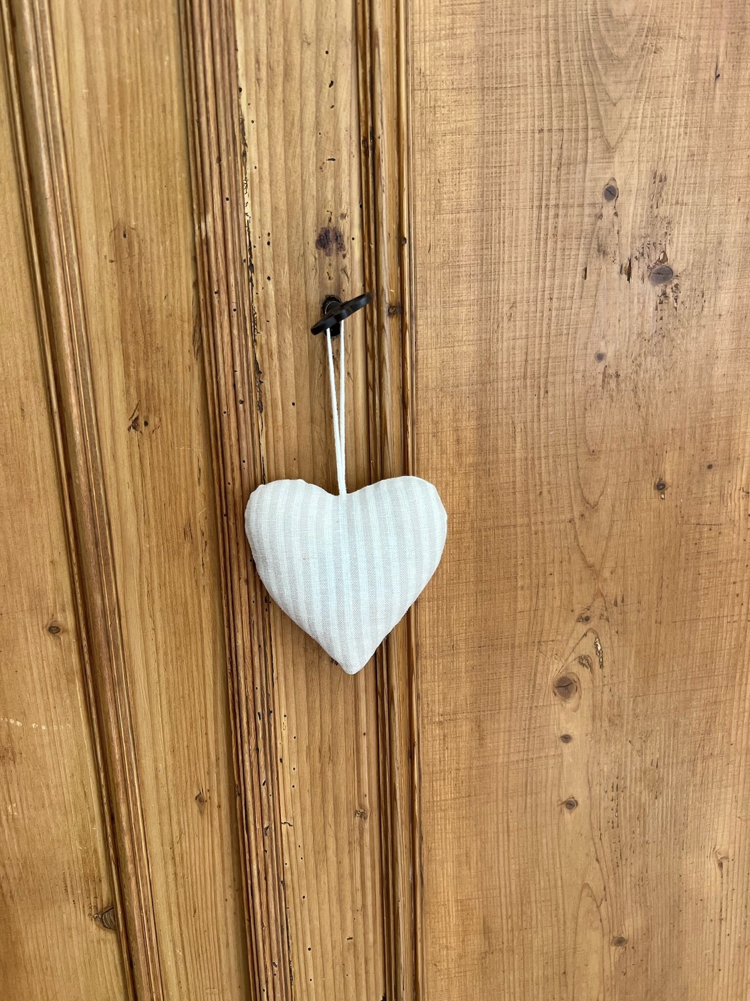 Un objet blanc en forme de cœur, suspendu à une surface en bois.