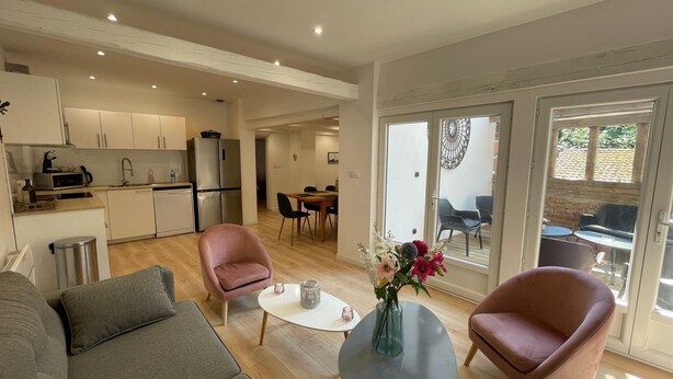 Un salon moderne comprenant un canapé, deux fauteuils, une table basse et un coin repas avec une table et des chaises.