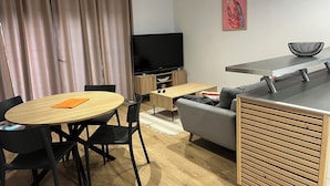 Una sala de estar moderna con un televisor de pantalla plana, una mesa de comedor redonda y un sofá.