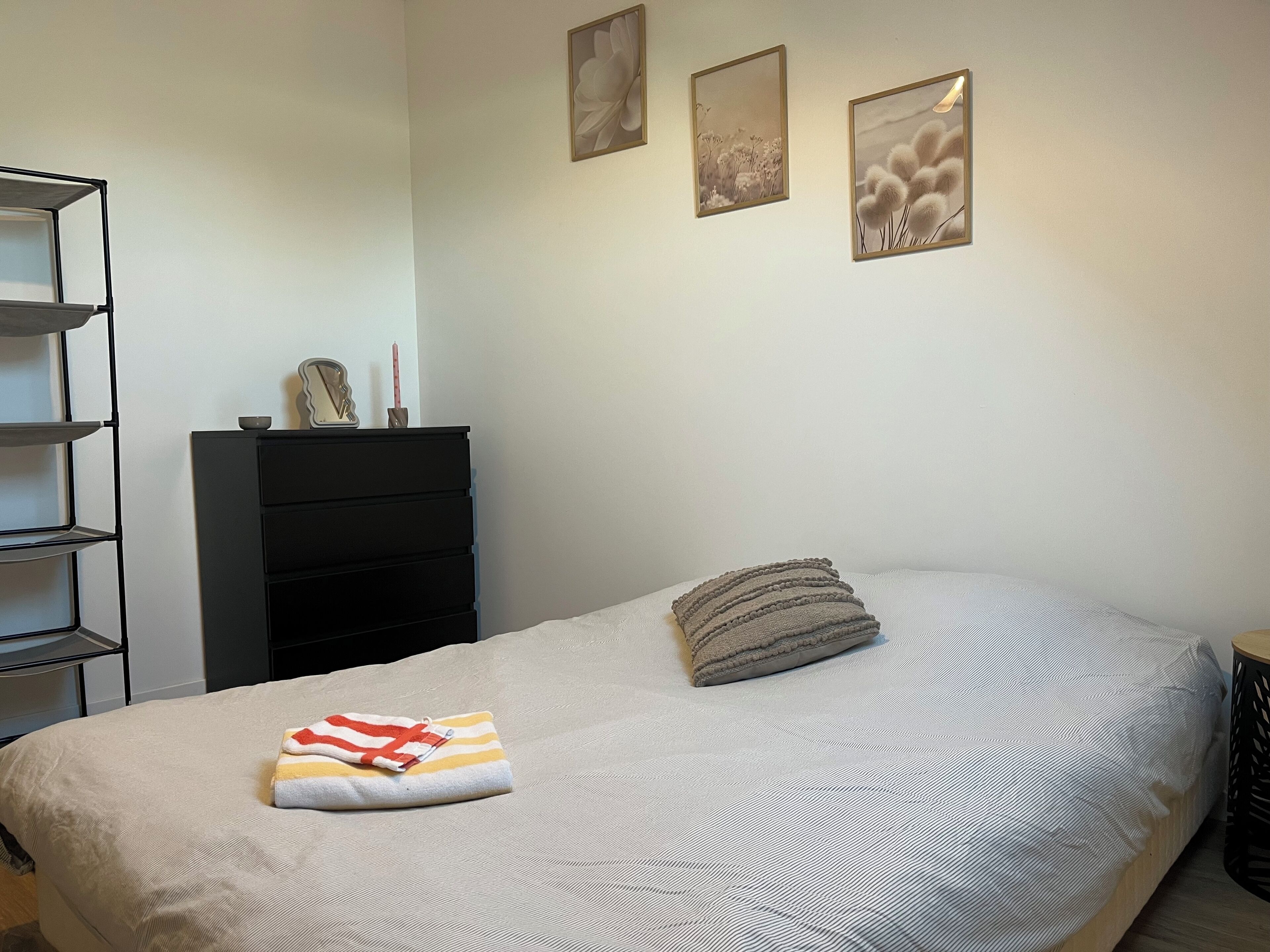 A bedroom with a bed, a dresser, and three framed pictures on the wall.
