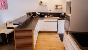 Una cocina moderna con una encimera larga, armarios blancos y un lavavajillas integrado.
