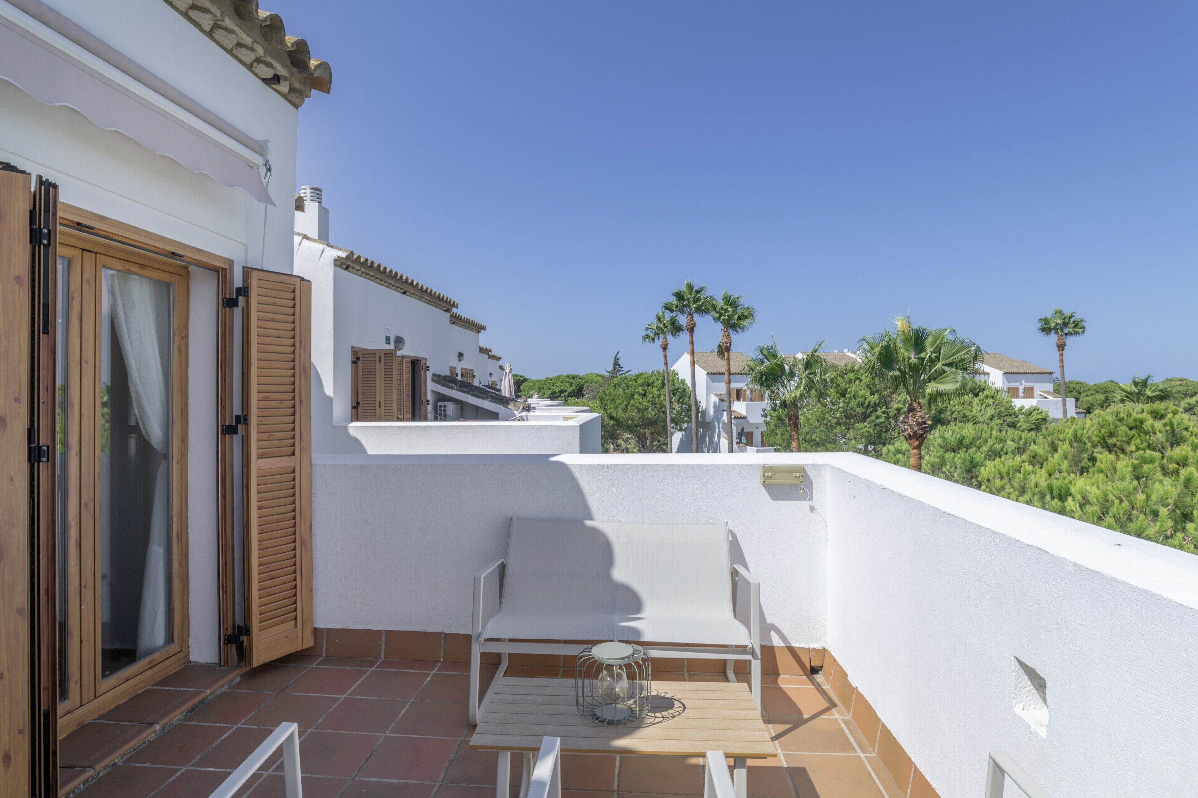 A balcony with a white chair, a small table, and a glass door.