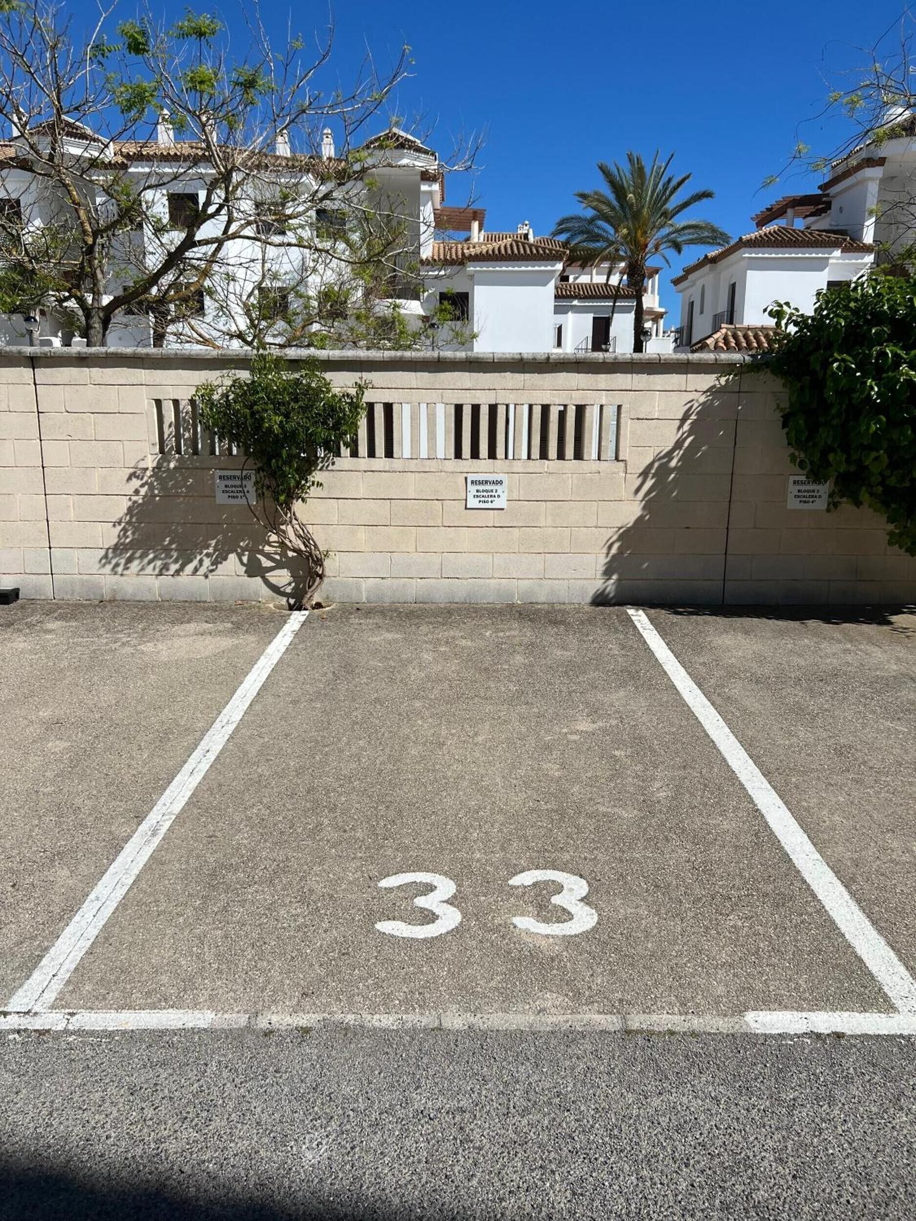 A parking area with a sign indicating reserved parking for block 3, floors 1-3, and a parking space marked with the number 33.