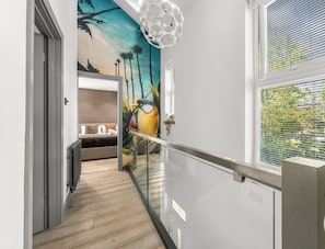 A modern interior with a wooden floor, a glass railing, and a mural of a bird and palm trees.