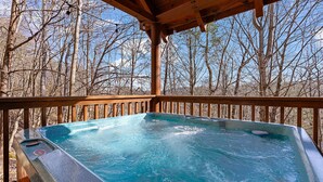 A hot tub on a wooden deck with a forest view. - Southern Memories – 2BR Cabin, Resort Pool, King Beds, Game Room (Pigeon Forge)