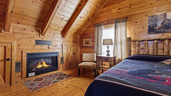 Une chambre confortable dans un chalet en rondins, avec une cheminée, un lit, une chaise et une table.