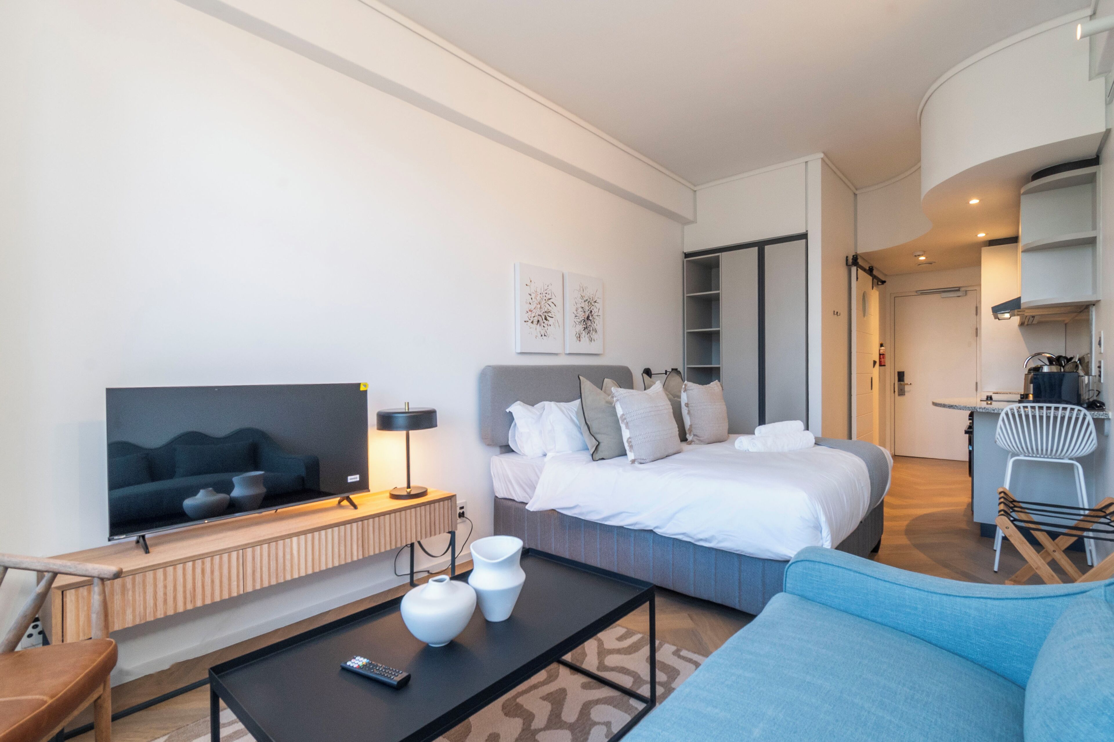 A modern hotel room with a large bed, a TV, a coffee table, and a seating area.