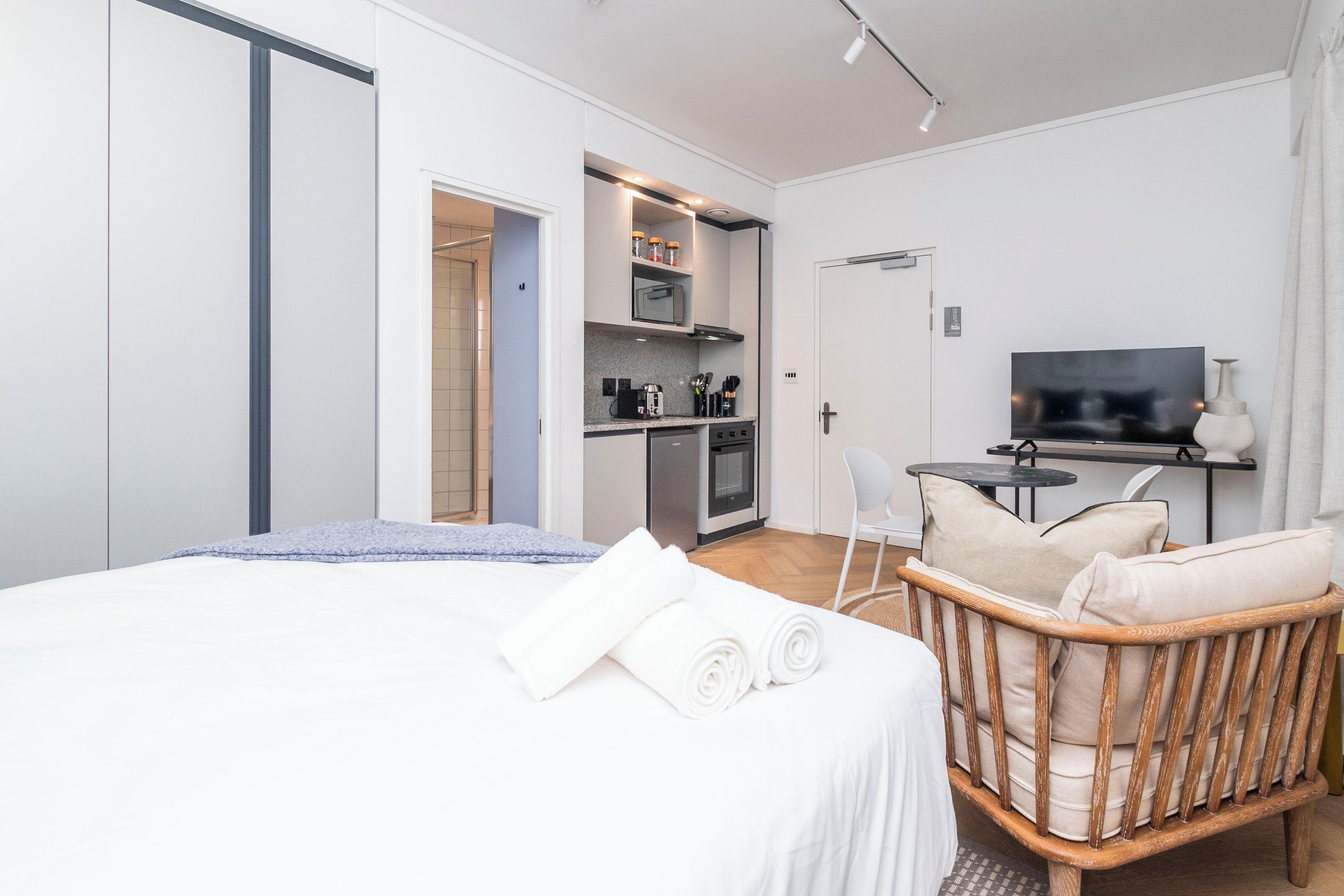 Et moderne hotelværelse med seng, træstol, tekøkken og fjernsyn.