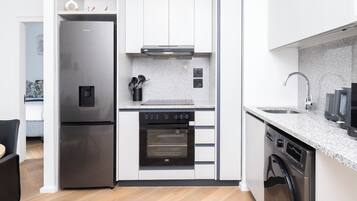 A compact kitchen with a built-in oven, dishwasher, and a refrigerator.