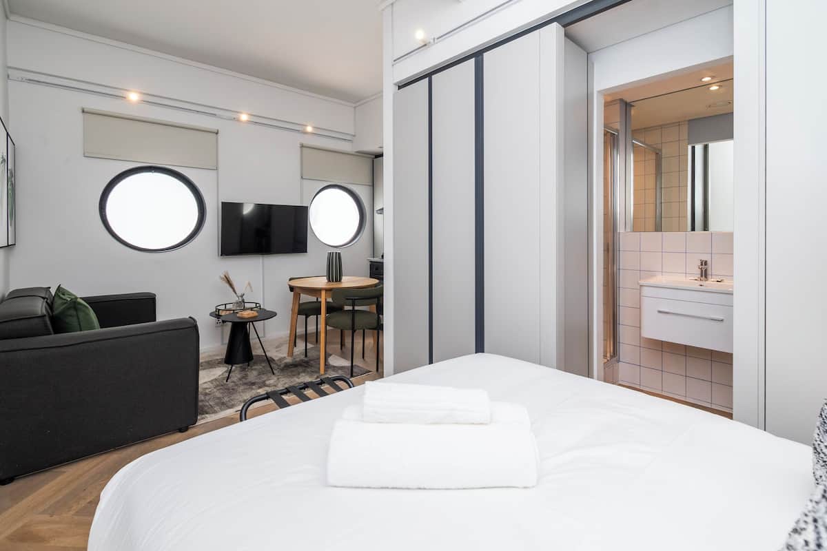 Een moderne hotelkamer met een groot bed, een bank, een klein rond tafeltje en een televisie.