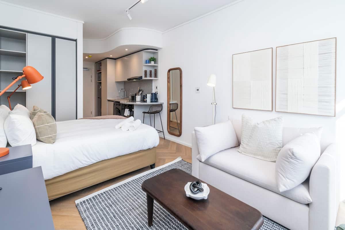 Een moderne hotelkamer met een bed, een bank, een bureau en een kitchenette.