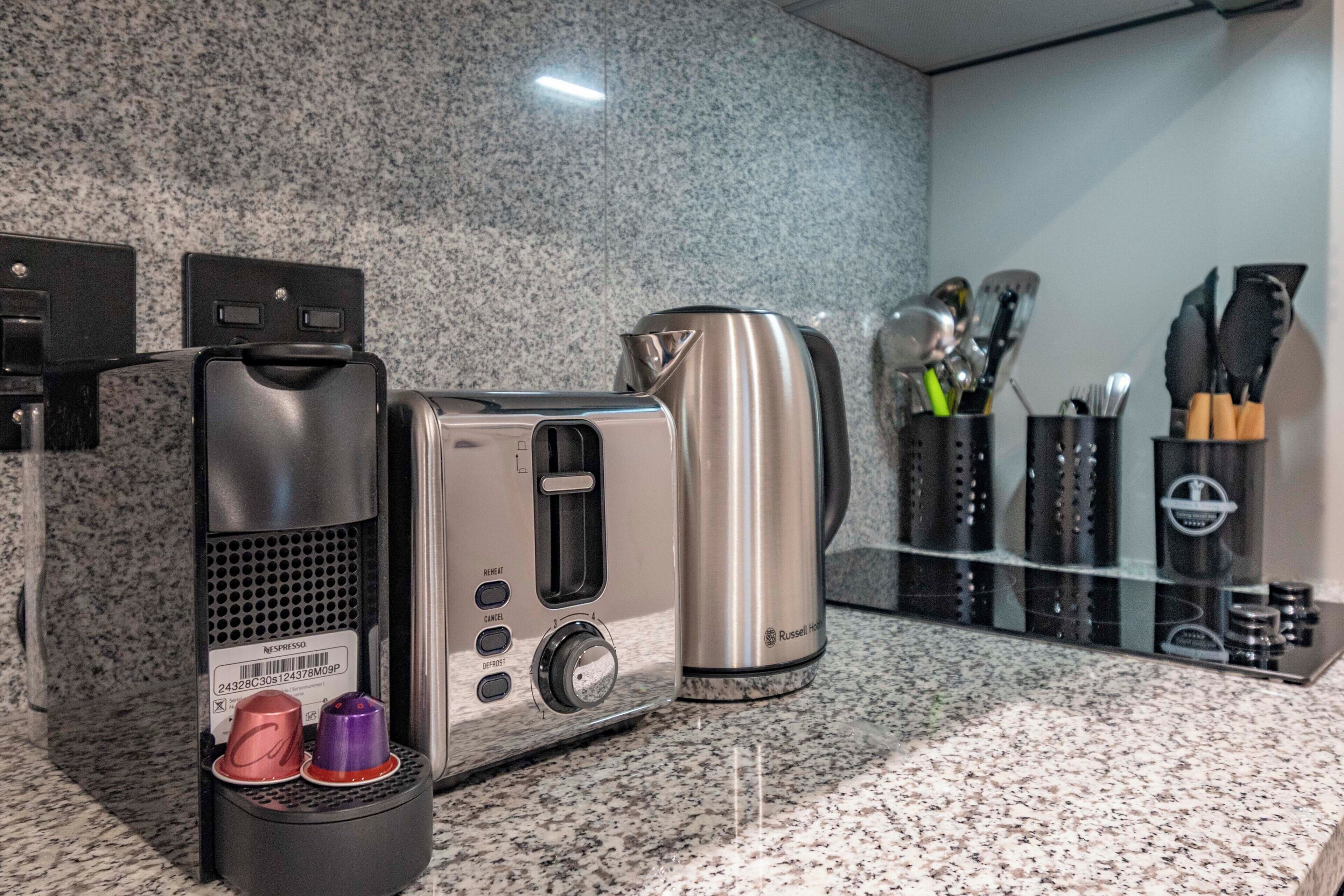 Une cuisine équipée d’une machine à café, d’une bouilloire et d’un porte-tasses contenant deux tasses.