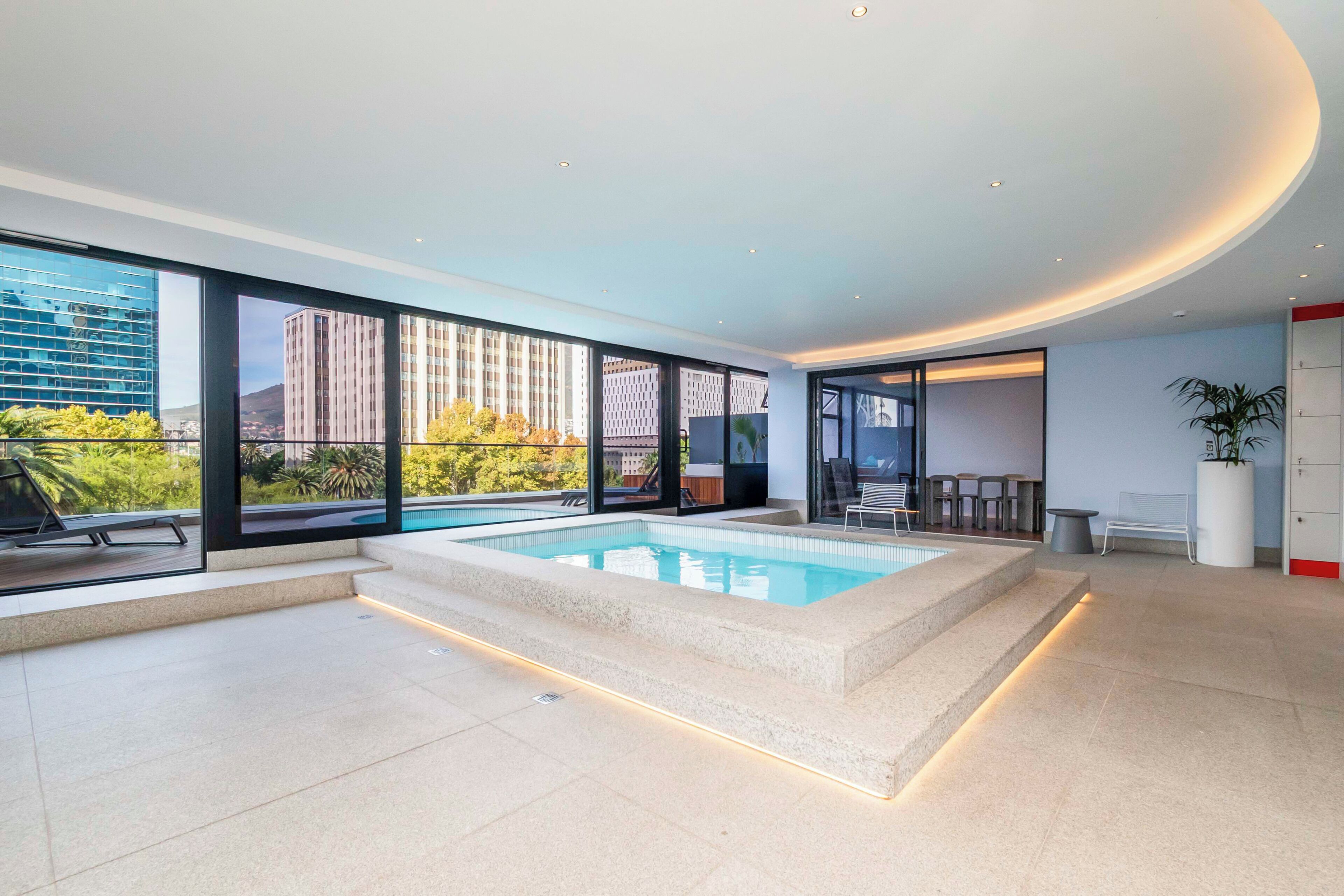 Ein moderner, überdachter Pool mit Blick auf Stadtgebäude und Grünflächen.