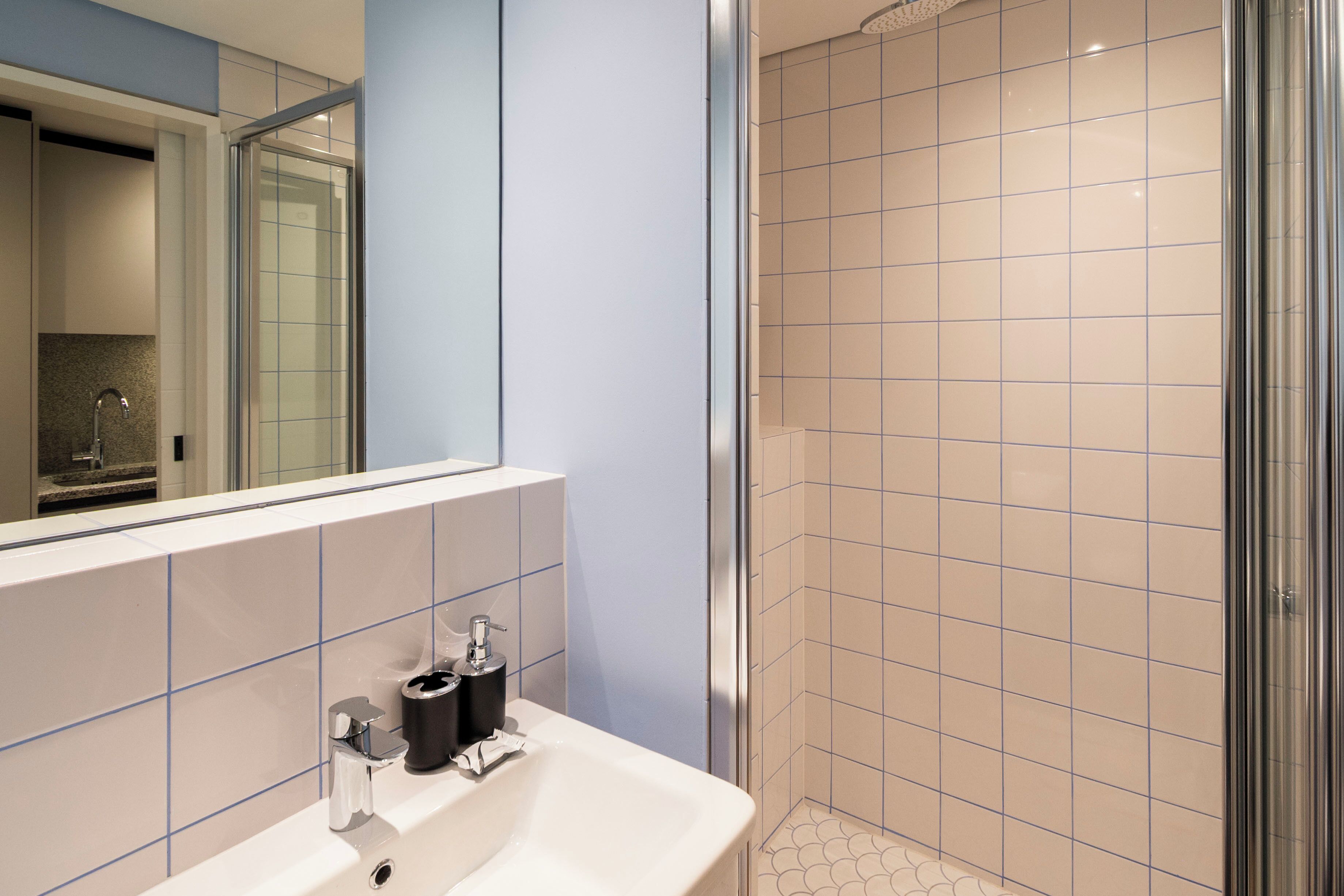 A modern bathroom with a sink, mirror, and shower.