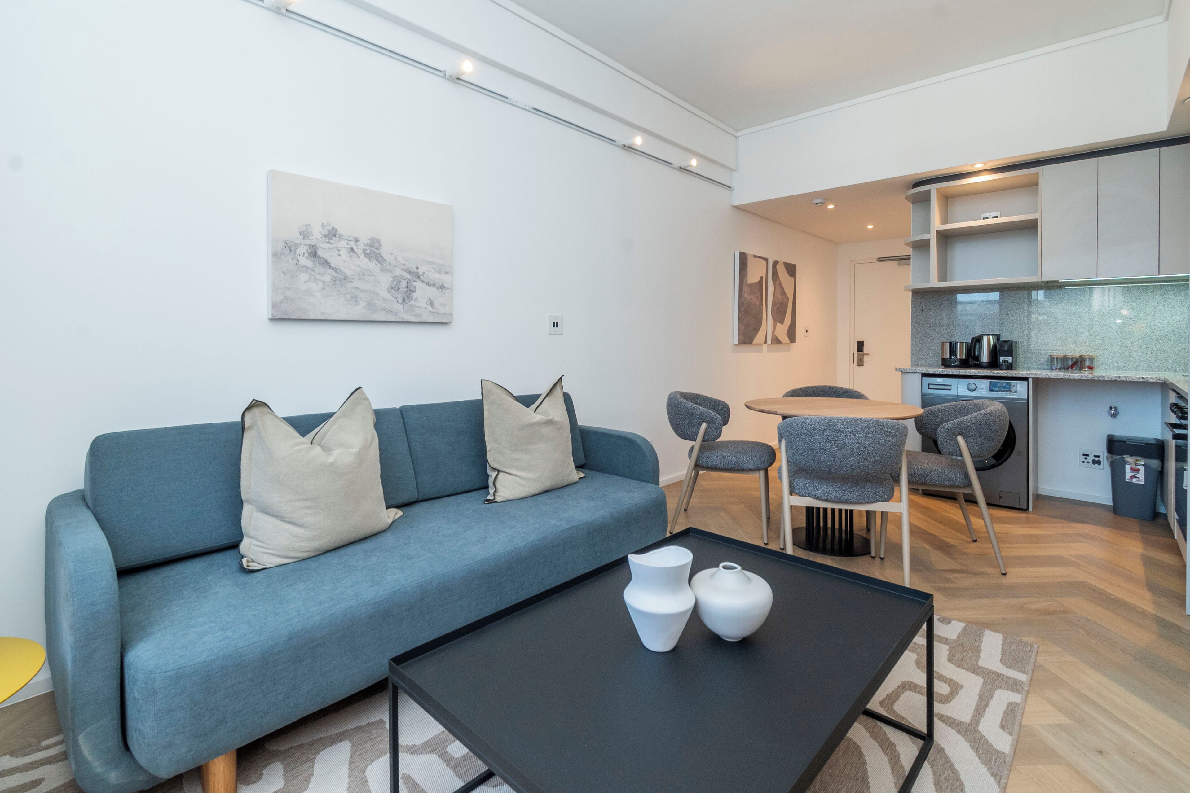 Un salon moderne avec un canapé bleu, deux vases blancs et une table basse noire.
