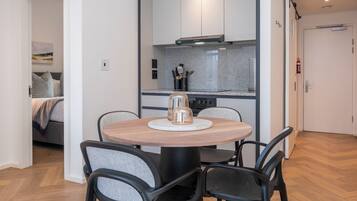 A modern kitchen with a round dining table and chairs, a built-in stove, and a small island with a coffee maker.