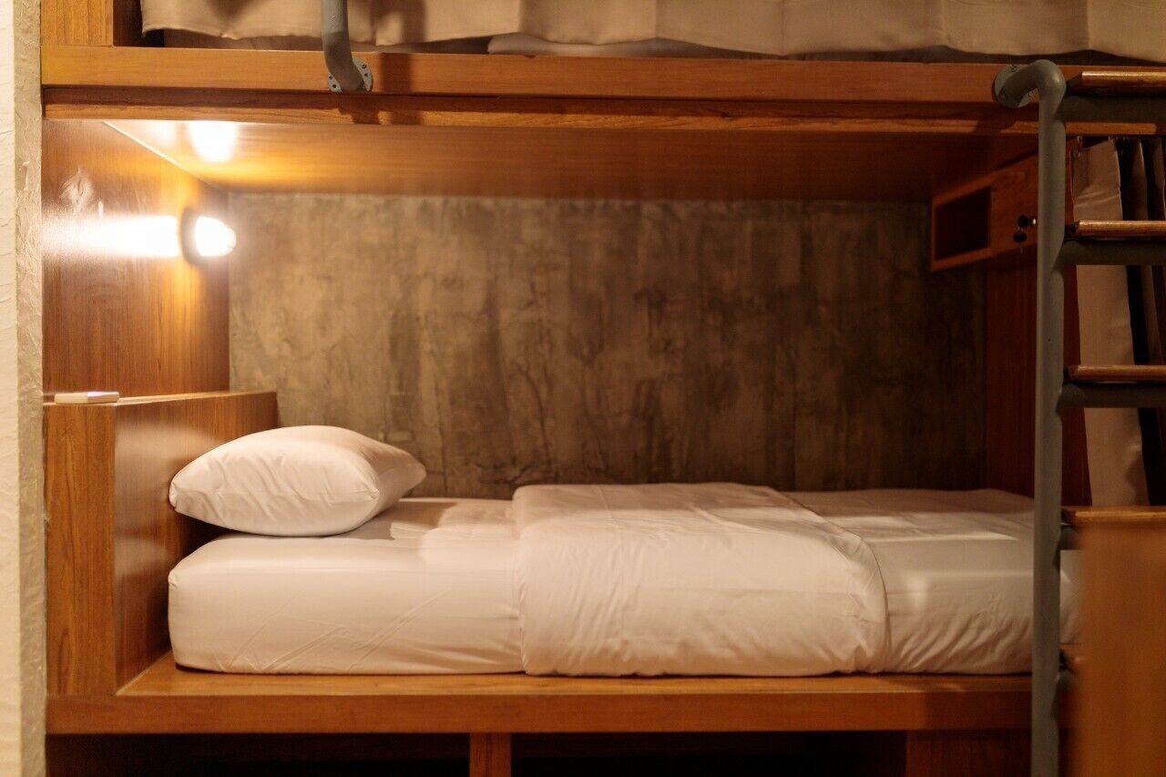 Una cama individual con ropa blanca y cabecera de madera.