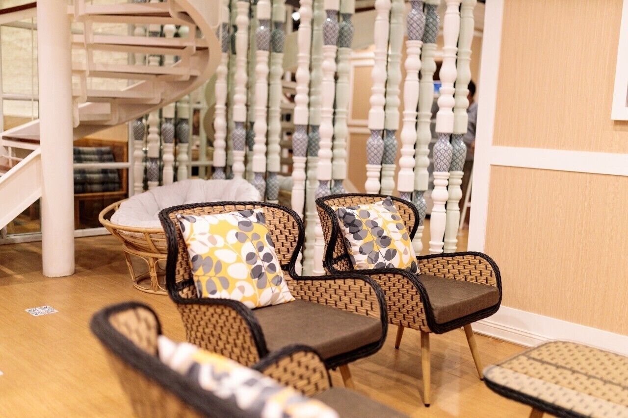 A modern interior with wicker chairs, patterned cushions, and a spiral staircase.
