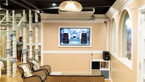 A hotel lobby with a staircase, seating area, television, and a speaker. - ReRe Hostel (Bangkok)