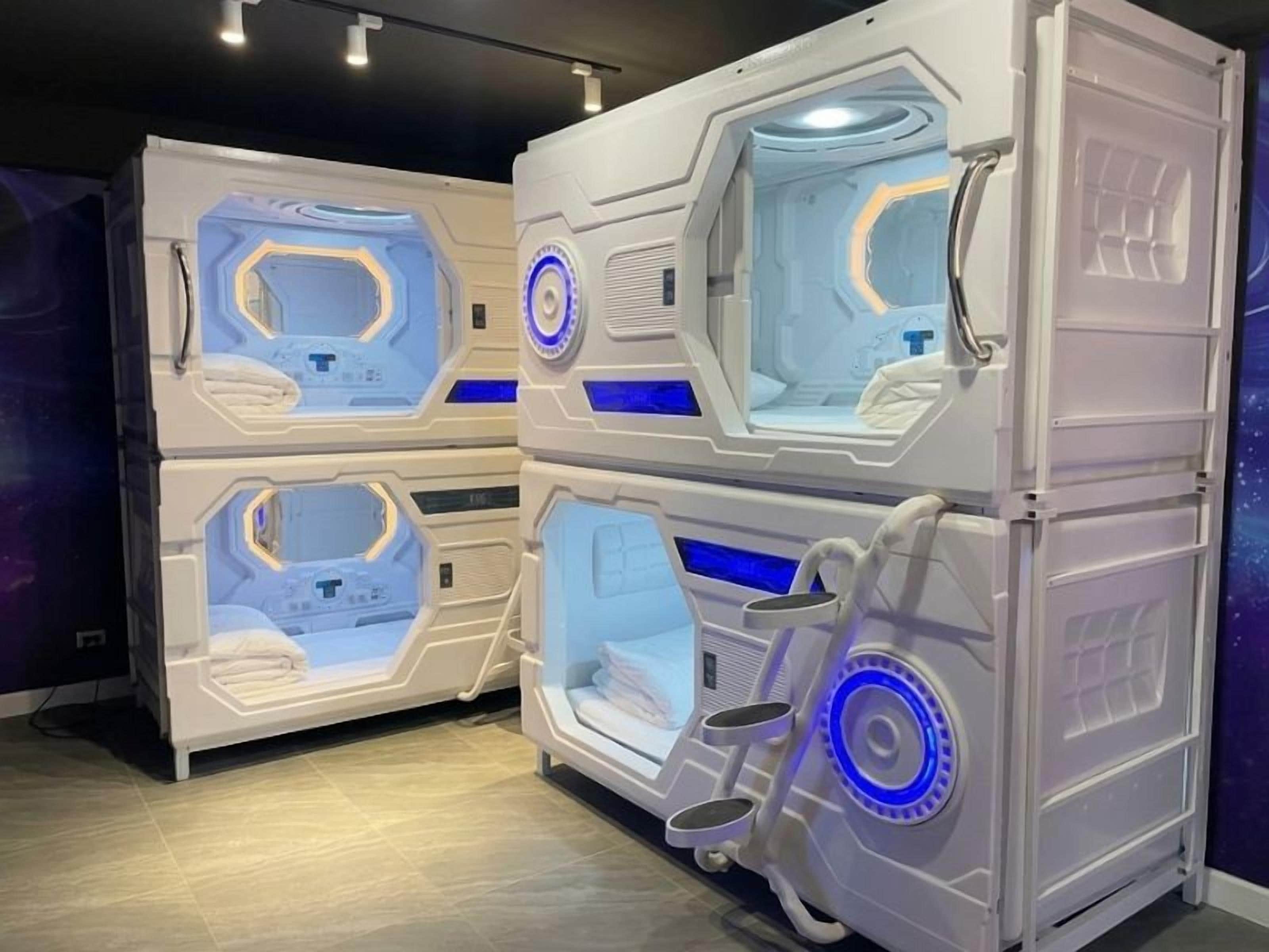 A room with two bunk beds, each with a control panel and a window.