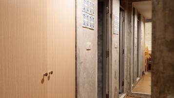 Un pasillo con pisos de madera, una puerta con manija y una pared de azulejos con un cartel.