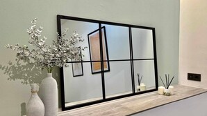 A modern interior with a large framed artwork on the wall, two vases with plants, and a small table with candles. - Mena Trip Malaga- Studio in the historic center (Málaga)