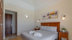 A bedroom with a bed, two bedside tables, a painting, and a door.