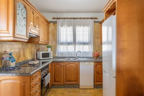 Una cocina con armarios de madera, microondas, lavavajillas y refrigerador.