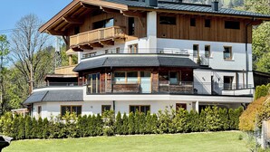 A multi-story chalet with wooden balconies, a sloped roof, and a well-maintained garden. - Apartment Almhütte SKI IN - SKI OUT (Brixen im Thale)