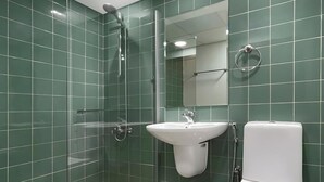 Et moderne badeværelse med et glasafskærmet brusebad, en hvid vask og et toilet.