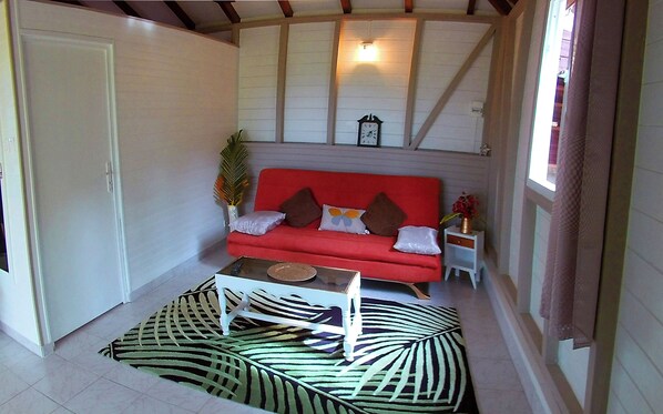 Un salon chaleureux avec un canapé rouge, une table basse et un tapis à motifs.