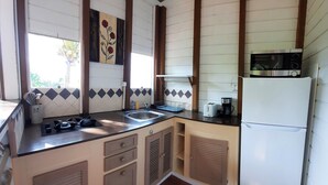 A compact kitchen with a sink, stove, and microwave. - 🌿 KACHIMAN Country Cottage 🌿 (Saint Esprit)