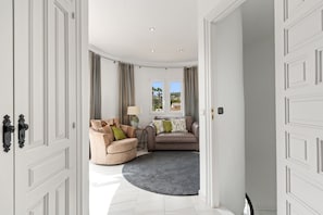 A spacious room with a large window, a round rug, and two sofas.