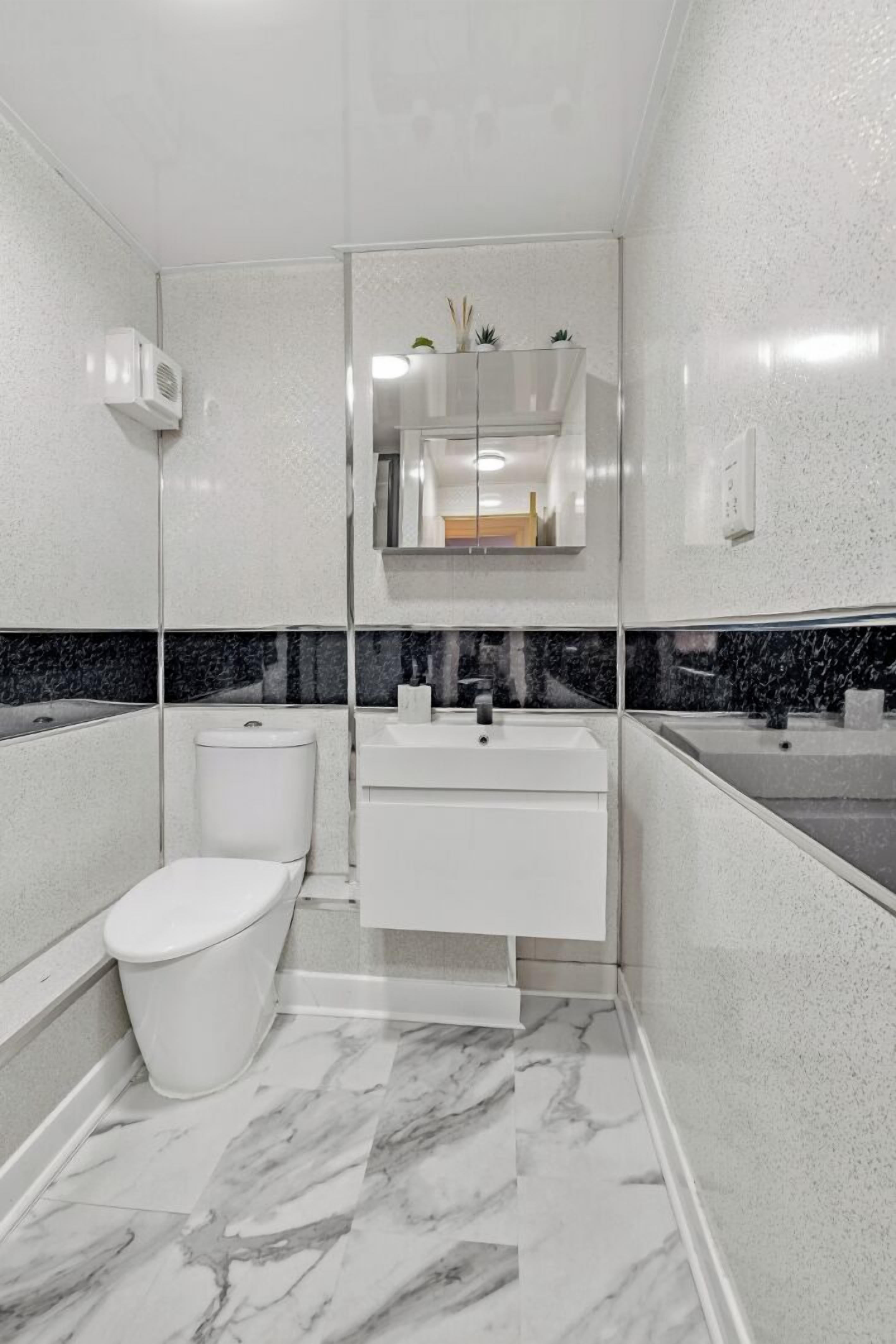 A modern bathroom with a white toilet, a sink, and a mirror.