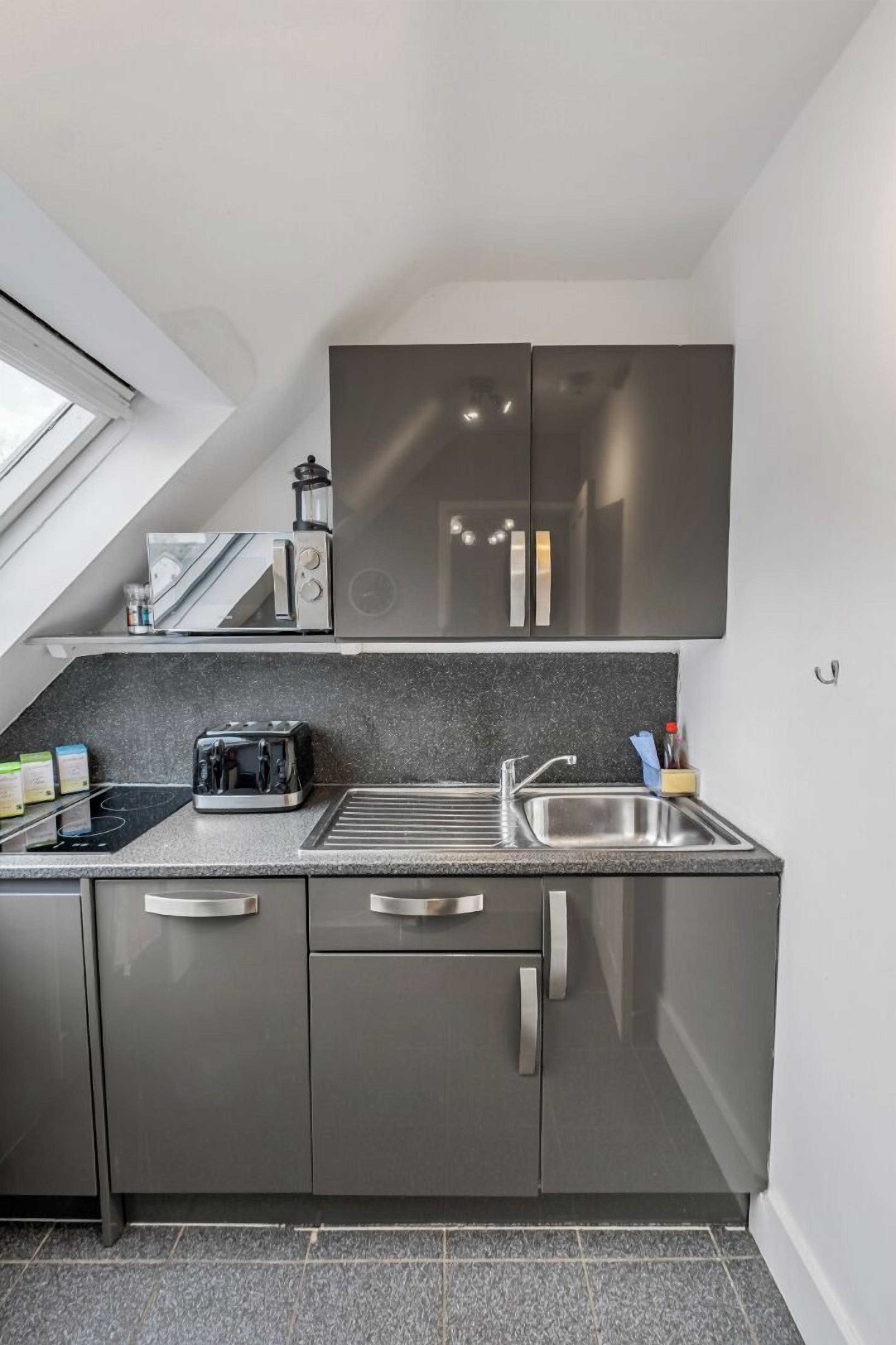 A modern kitchen with a built-in oven, a toaster, a sink, and a window above the countertop.