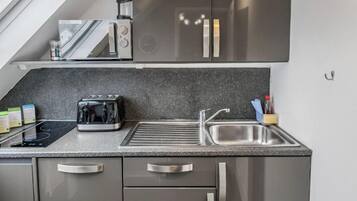 A modern kitchen with a built-in oven, a toaster, a sink, and a window above the countertop.