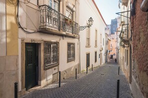 A narrow cobblestone street flanked by buildings with barred windows and a green door.