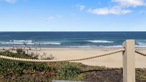 Una barrera de cuerda con vista al océano y la vegetación de la playa.