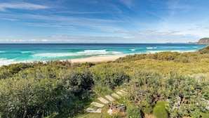 Un paisaje costero con playa, vegetación densa y cielo despejado.